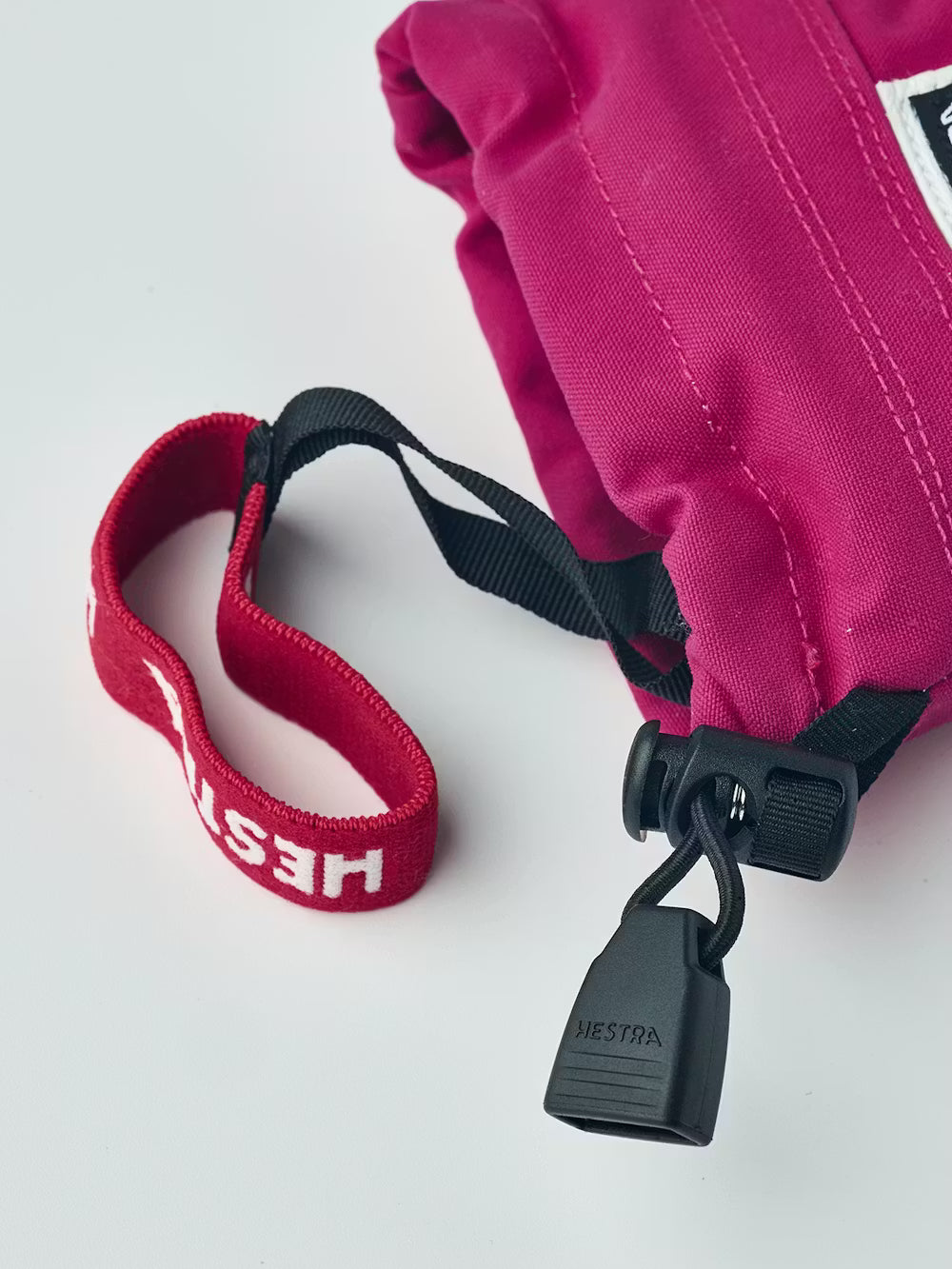 A pair of pink and white Hestra Junior Army Leather Heli Ski 3-Finger Gloves made from premium leather.