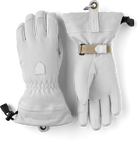  A pair of white Hestra Women’s Patrol Gauntlet Gloves, which are designed to keep your hands warm and dry in harsh winter conditions.