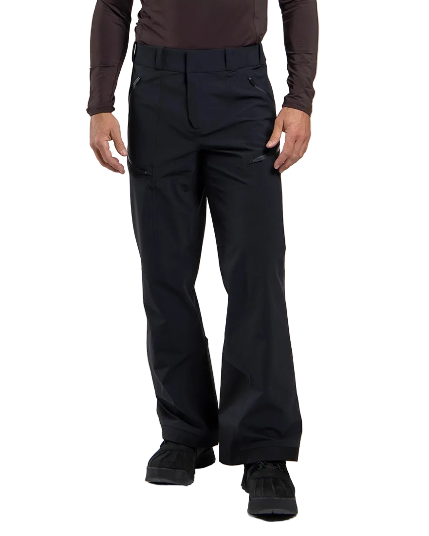 Front view of black Kjus Men’s FRX Lucas Shell Pants featuring 3-layer waterproof stretch fabric, zippered outer thigh vents, water-repellent zippers, and Schoeller Keprotec reinforced scuff guards.