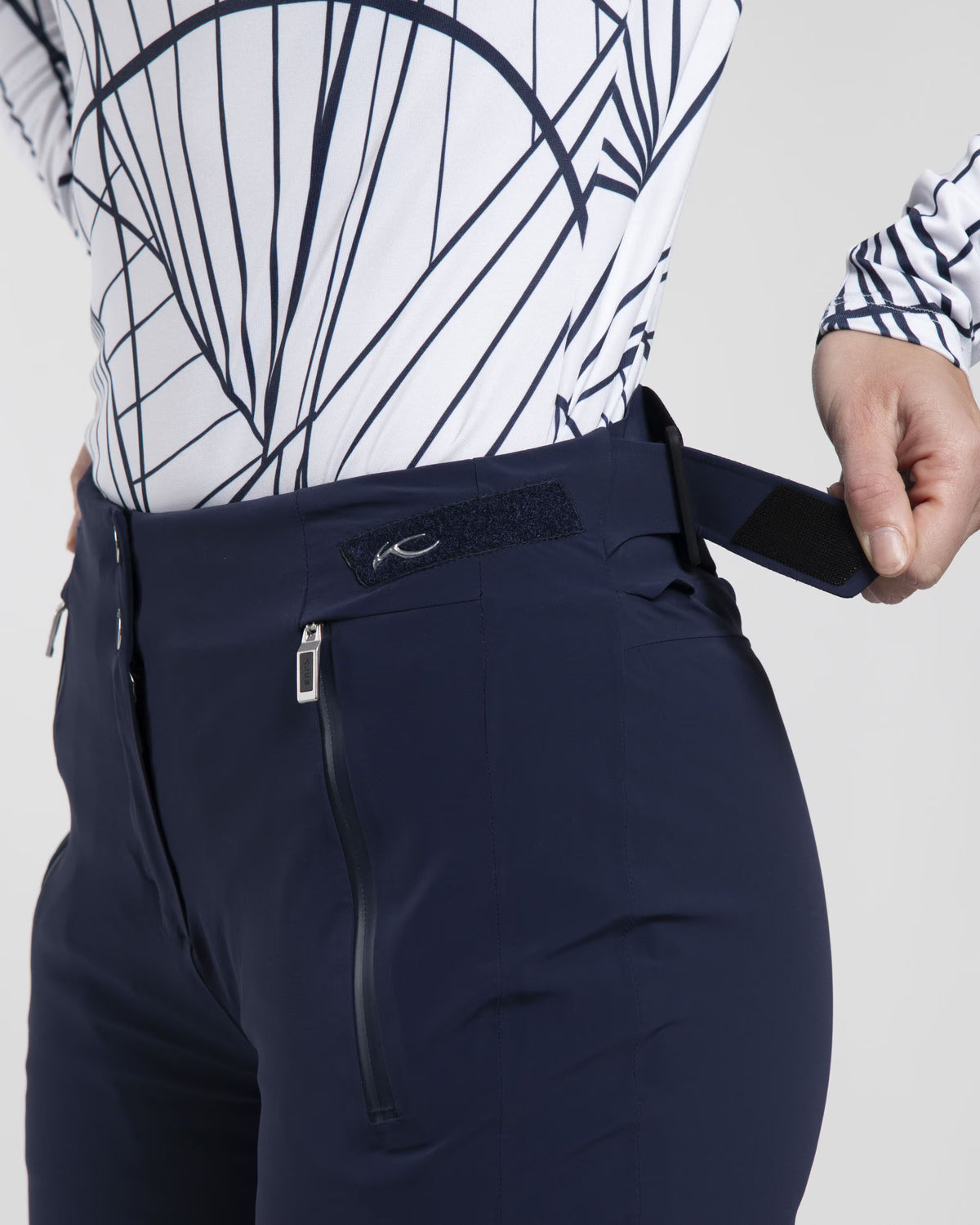 Front view of black Kjus Women’s Formula Pants featuring 4-way stretch waterproof fabric, Fast Thermo Core insulation, water-repellent zippers, and Schoeller Keprotec reinforced scuff guards.