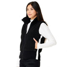 A woman wearing a black Krimson Klover Women's Ember Vest, designed to elevate winter outfits.