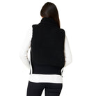 A woman wearing a black Krimson Klover Women's Ember Vest, designed to elevate winter outfits.
