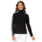 A woman wearing a black Krimson Klover Women's Slalom Zip Neck Sweater with white snowflake jacquard sleeve details and a quarter zip front.