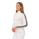A woman wearing a white Krimson Klover Women's Slalom Zip Neck Sweater with black snowflake jacquard sleeve details and a quarter zip front.