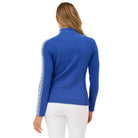A woman wearing a blue Krimson Klover Women's Slalom Zip Neck Sweater with white snowflake jacquard sleeve details and a quarter zip front.