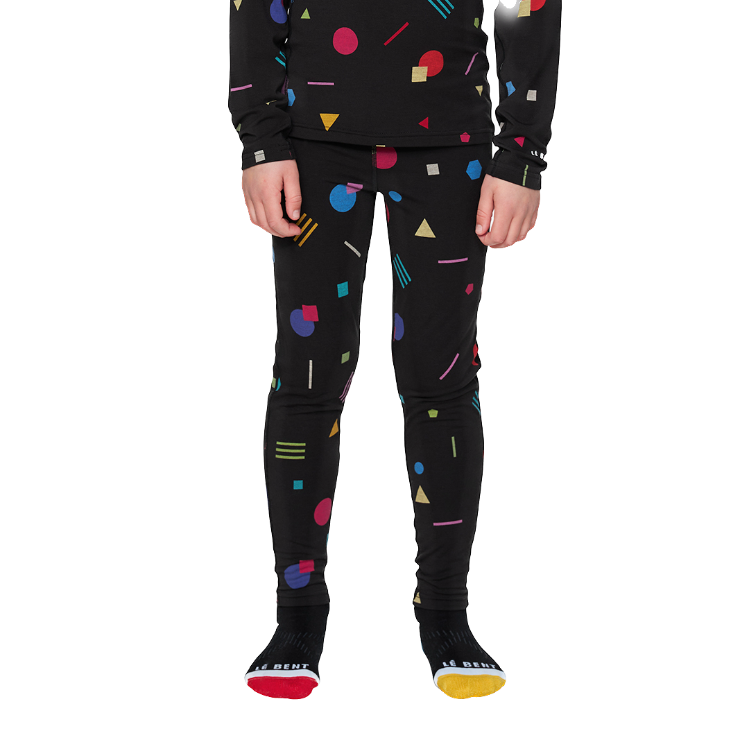 A child wearing a pair of black Le Bent Kids' Condetti Midweight baselayer bottoms with a colorful geometric pattern.