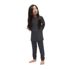 A child wearing a black Le Bent Kids' Core Midweight Raglan Crew Baselayer Top that is stretchable, breathable, and made from a premium bamboo and merino wool blend.