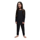 A child wearing a black Le Bent Kids' Core Midweight Raglan Crew Baselayer Top that is stretchable, breathable, and made from a premium bamboo and merino wool blend.