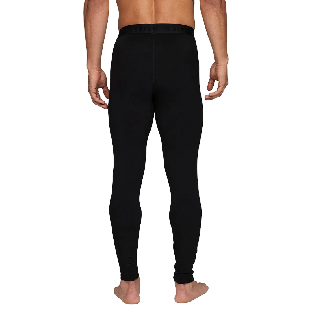 A man wearing a pair of Le Bent Men's Core Midweight Baselayer Bottoms that are made with a bamboo and merino wool blend.