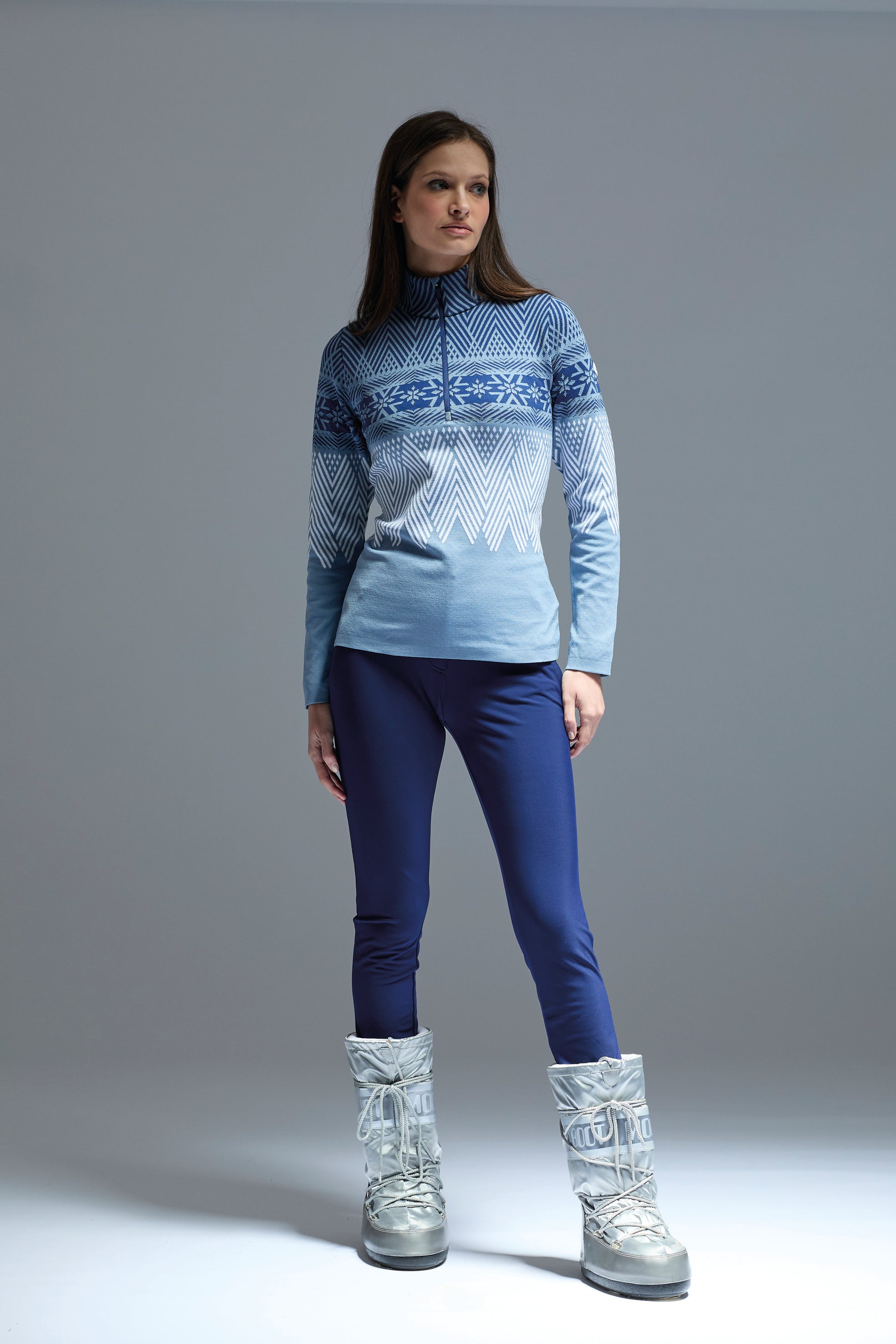A woman wearing a blue Newland Women's Are 1/2 Zip midlayer sweater that is moisture-wicking, breathable, and stretchable.