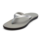 A silver Olukai Junior Girls Ho'opio flip-flop sandal with a grey sole on a white background