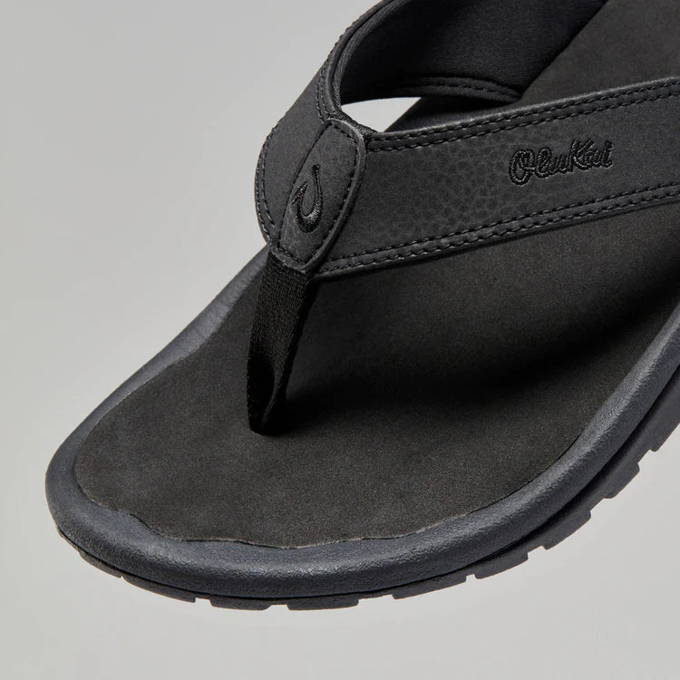 Black Olukai Men's Ohana flip-flop sandal with an Olukai logo on a white background