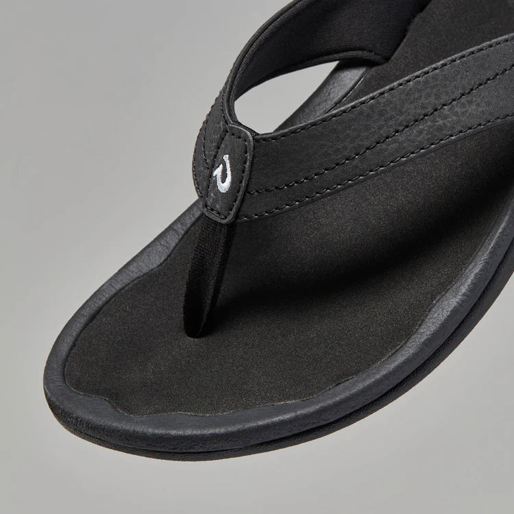A black Olukai Women's Ohana flip-flop sandal on a white background