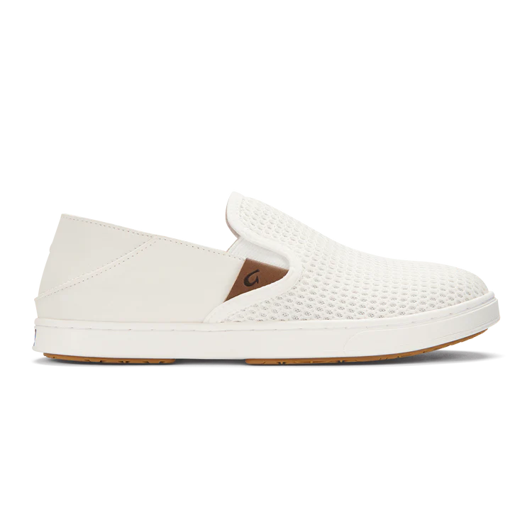 White Olukai Women's Pehuea slip-on shoe that features a collapsible heel with a white sole on a white background