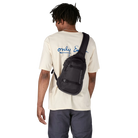 Man wearing a black Patagonia Atom Sling 8L Pack featuring 100% recycled ripstop fabric, an asymmetrical single-strap harness with a zippered phone pocket, breathable spacer-mesh back paneling, front zippered accessory pocket, and exterior tuck-away compression straps.