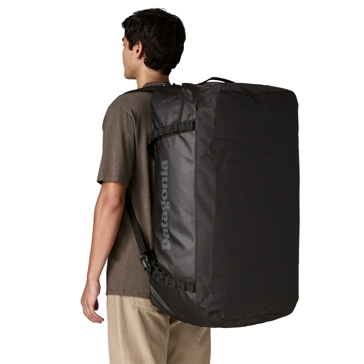 Rear view of the black on black Patagonia Black Hole Duffel 100L featuring weather-resistant TPU-laminated ripstop fabric, removable ergonomic backpack shoulder straps, reinforced end haul handles, a padded base, and heavy-duty exterior daisy chain lash loops.