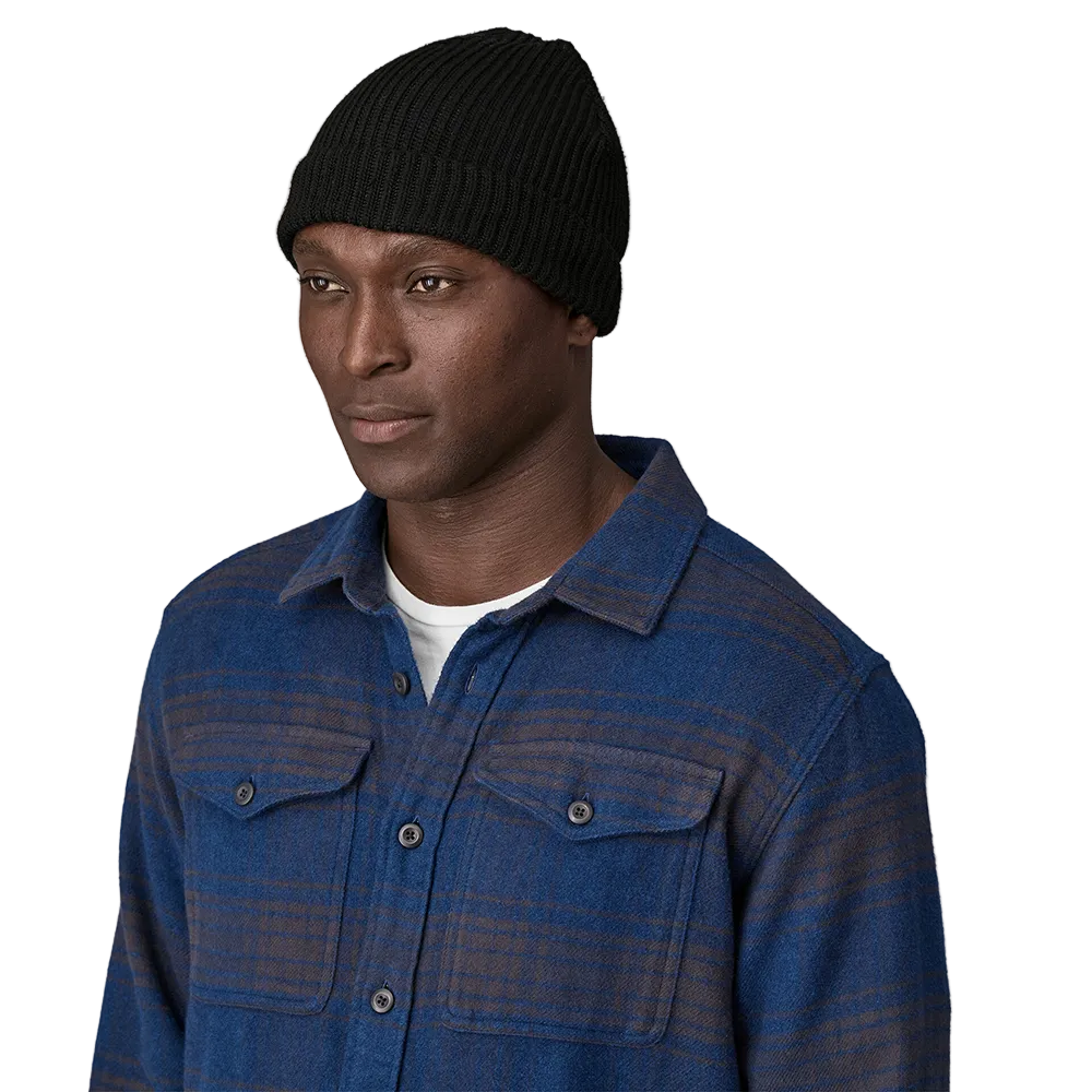 Front view of a black Patagonia Fisherman's Rolled Beanie featuring 100% recycled polyester 1x1 rib-knit construction, an adjustable roll-up cuff, and a woven logo label.