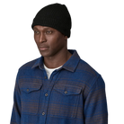 Front view of a black Patagonia Fisherman's Rolled Beanie featuring 100% recycled polyester 1x1 rib-knit construction, an adjustable roll-up cuff, and a woven logo label.