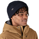 Front view of a navy blue Patagonia Fisherman's Rolled Beanie featuring 100% recycled polyester 1x1 rib-knit construction, an adjustable roll-up cuff, and a woven logo label.