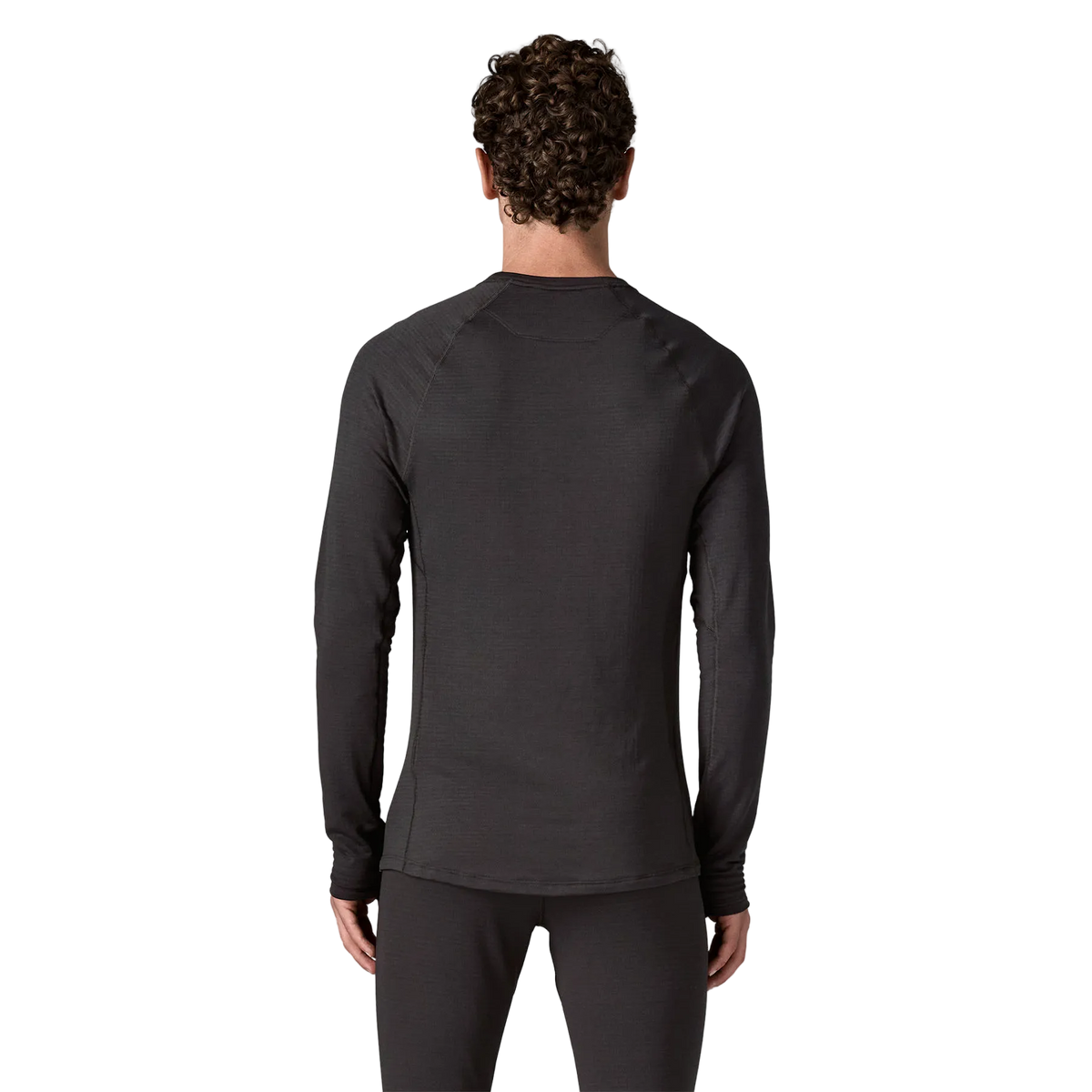 Rear view of the black Patagonia Men's Capilene Thermal Weight Crew Baselayer featuring Polartec Power Grid fabric with an open-grid brushed interior, a self-fabric crewneck, offset shoulder seams, full underarm gussets, flatlock seam construction, elastic thumb loops, and a subtle drop-tail hem.