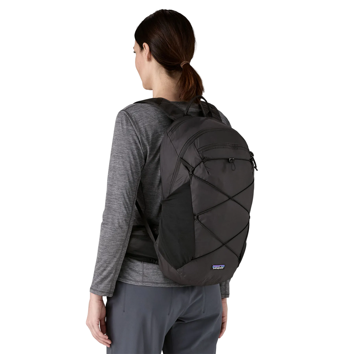 Rear view of a black Patagonia Terravia Pack 22L featuring 100% recycled nylon ripstop fabric, breathable Regulator airmesh shoulder straps, a front quick-stash pocket, dual side stretch water-bottle pockets, and trekking pole attachment loops.