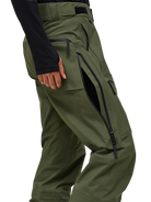 Side view of the pine needle green Peak Performance Men's GORE-TEX C-Knit 3L Shell Pants featuring 3-layer GORE-TEX fabric with C-KNIT backer technology, YKK AquaGuard leg ventilation zips, an adjustable velcro waistband, and reinforced Cordura lower leg scuff guards.