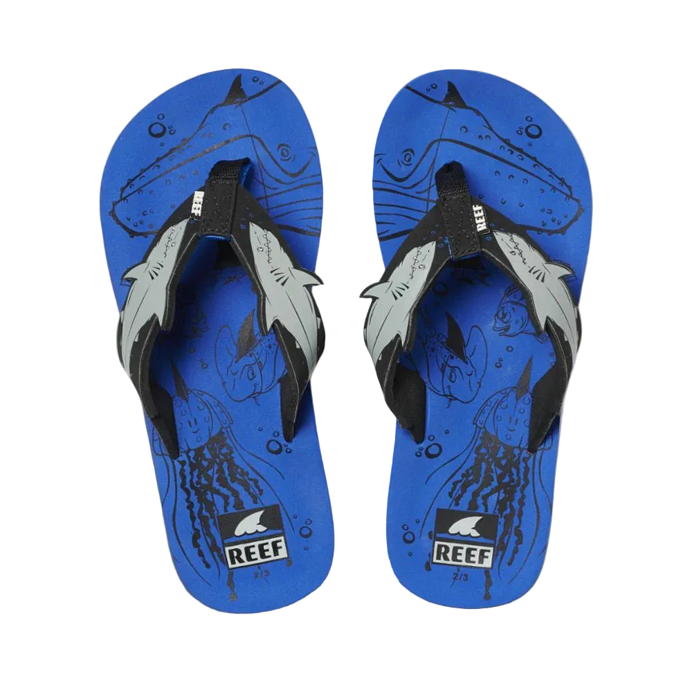 Pair of blue Reef Junior Ahi Blue Shark flip-flops with shark design and Reef logo on a white background