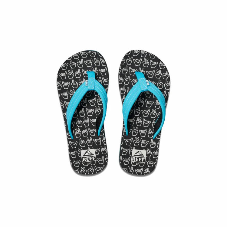 Pair of black Reef Junior Ahi Shaka Glow flip-flops with a white shaka pattern and blue straps on a white background