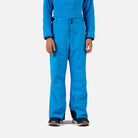 A boy wearing a pair of blue Rossignol Boys' Insulated Ski Pants that are waterproof, breathable, and stretchable.