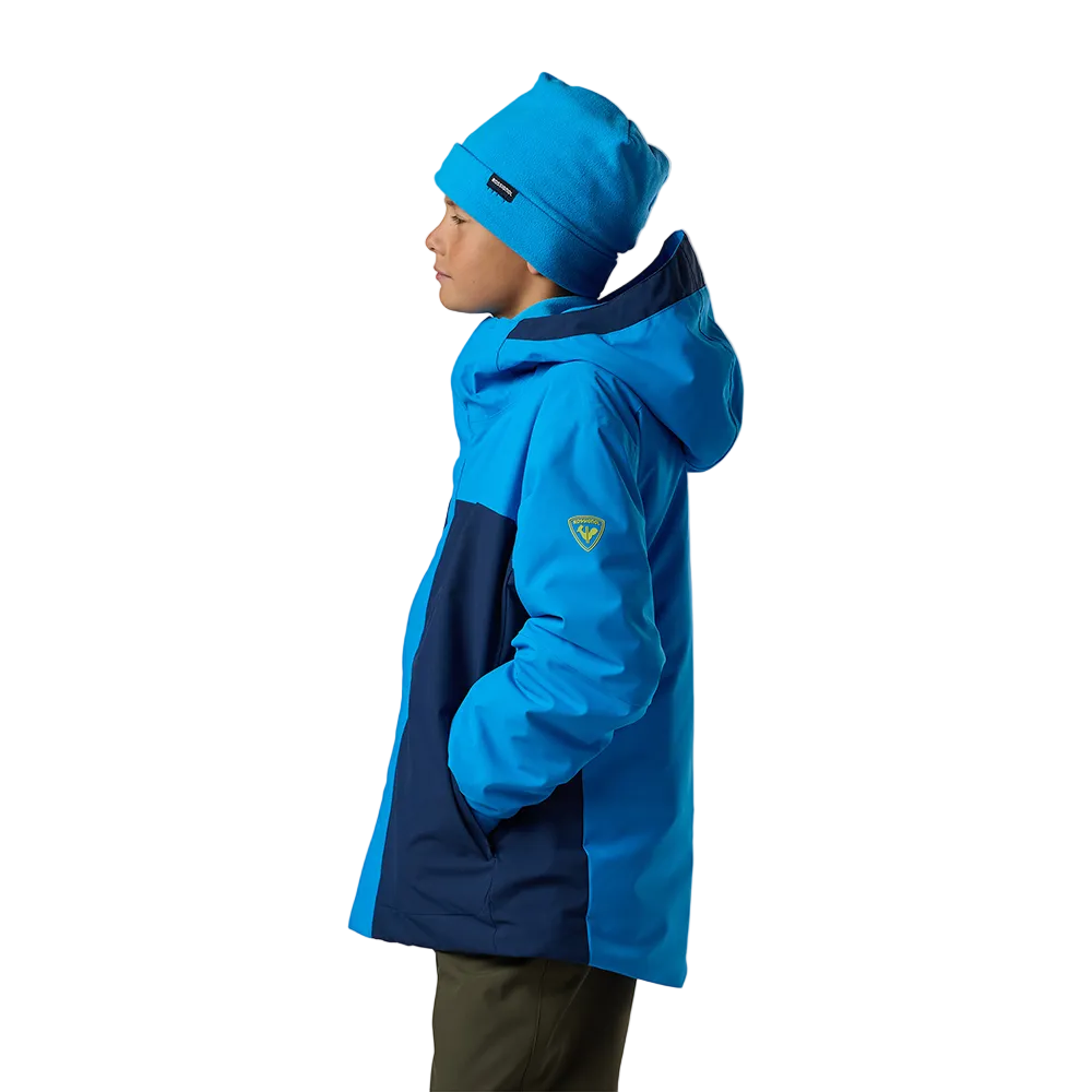Side view of a blazing blue Rossignol Jr Strawpile Insulated Jacket featuring waterproof membrane fabric, body-mapped recycled synthetic insulation, adjustable hood, integrated powder skirt, and zippered sleeve pass pocket.