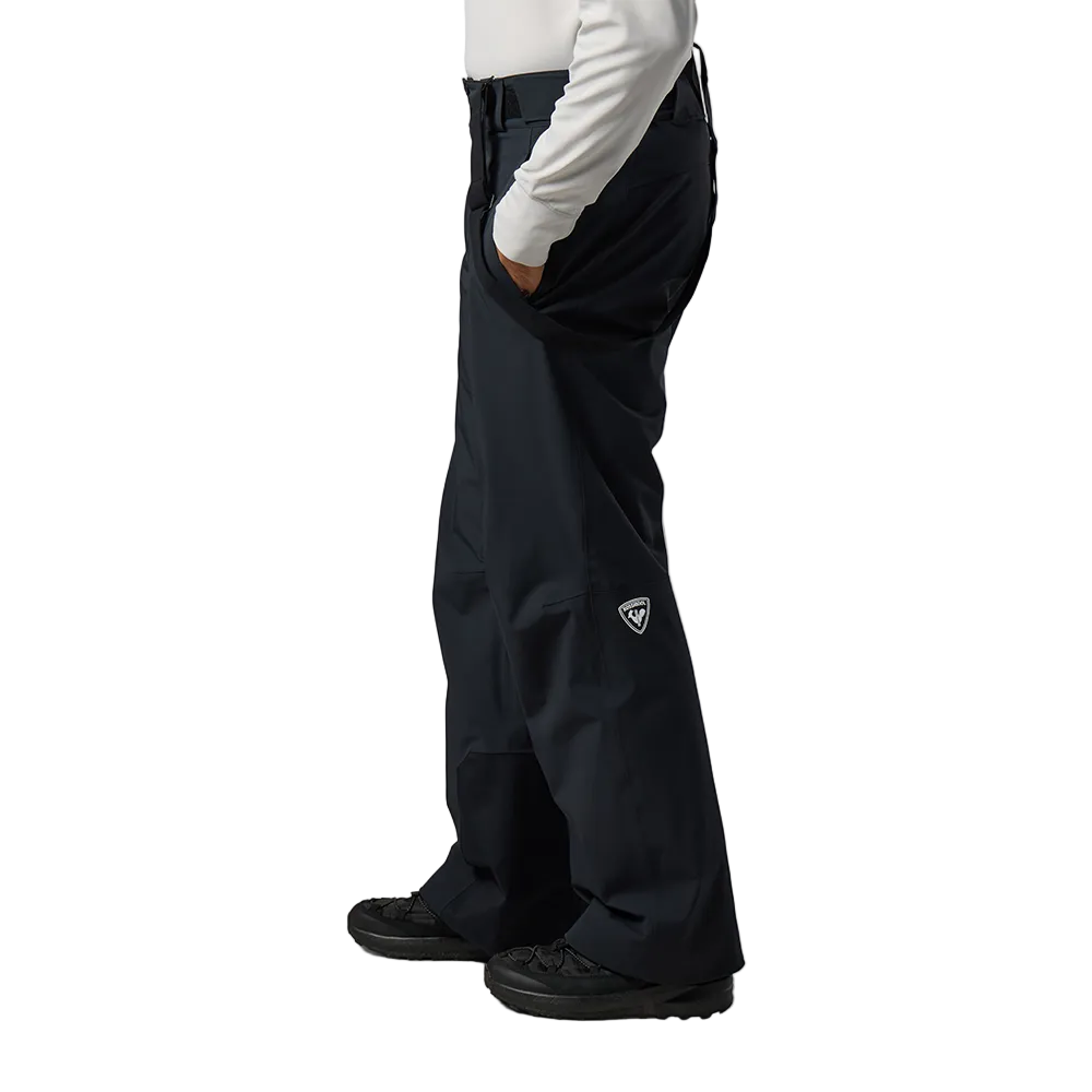 Side view of black Rossignol Men’s 4WS Blackside Insulated Pants featuring four-way stretch waterproof membrane fabric, synthetic insulation, adjustable waist tabs, zippered leg vents, integrated boot gaiters, and reinforced hem scuff guards.