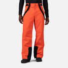 A man wearing a pair of orange Rossignol Men's Insulated Ski Pants that are waterproof, breathable, stretchable, and warm.