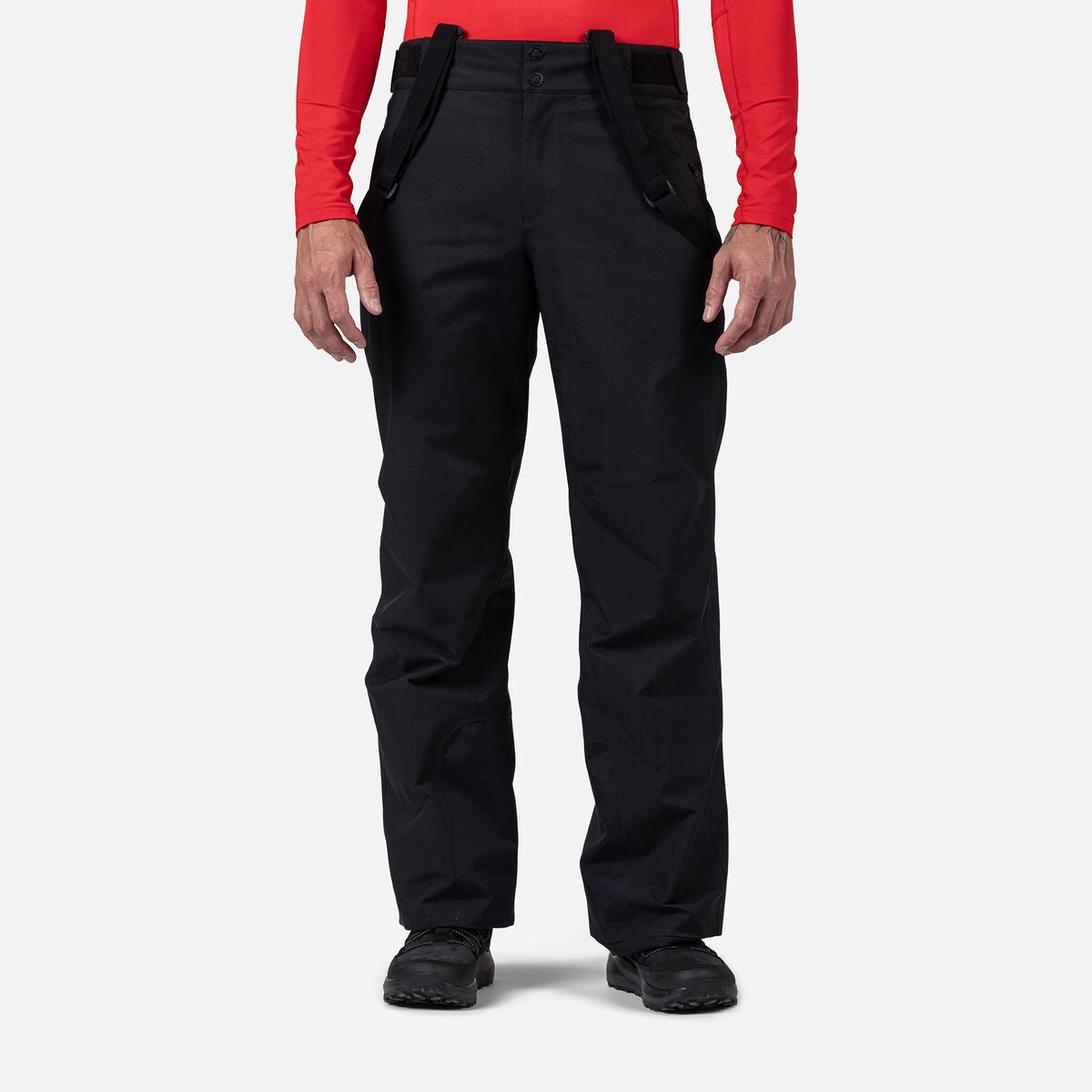 A man wearing a pair of black Rossignol Men's Insulated Ski Pants - Short, which feature a 30 inch inseam and are waterproof, breathable, stretchable, and warm.