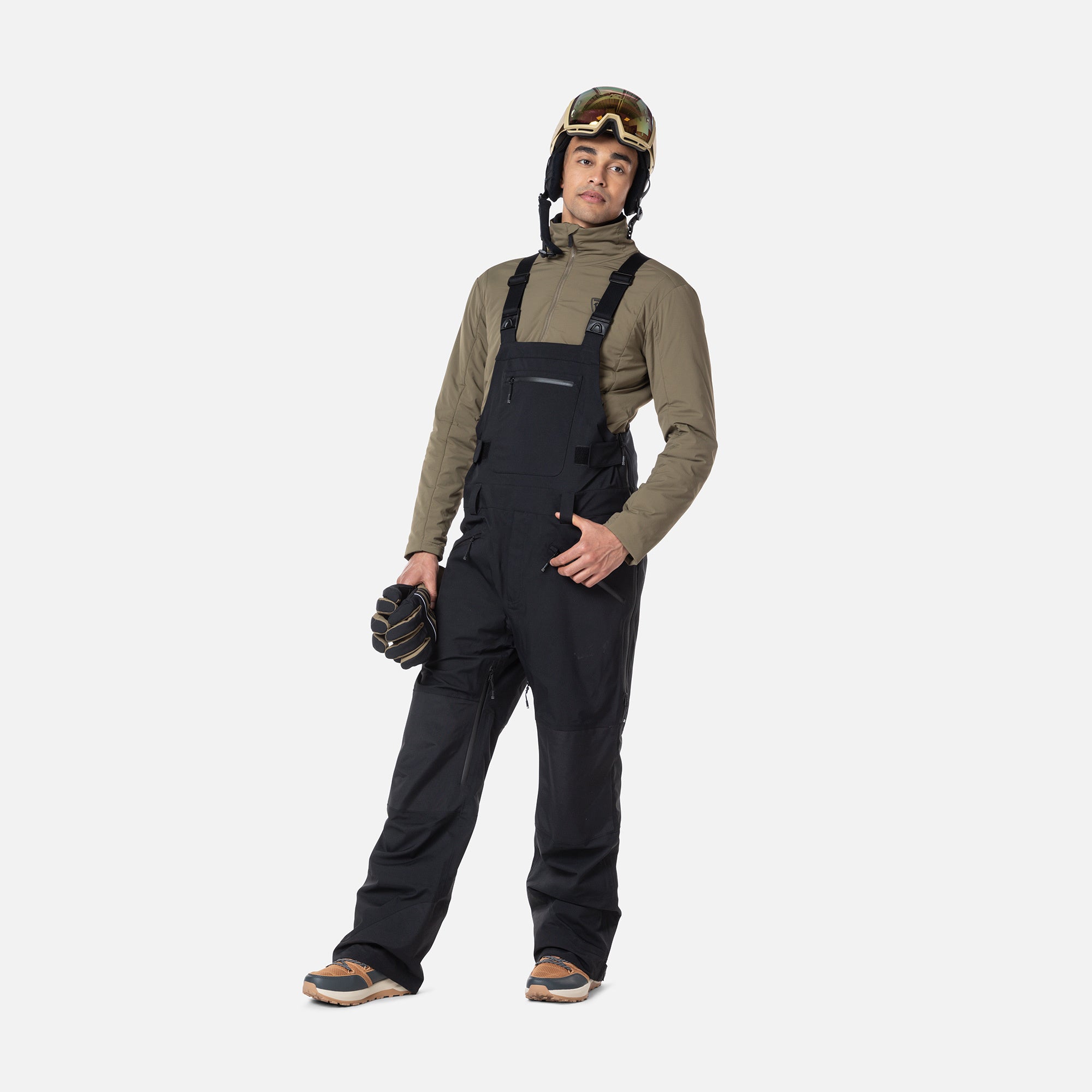 A man wearing a pair of black Rossignol Men's SKPR 3L AYR Bib Pants that are waterproof, breathable, stretchable, and warm.