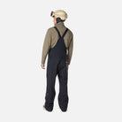 A man wearing a pair of black Rossignol Men's SKPR 3L AYR Bib Pants that are waterproof, breathable, stretchable, and warm.