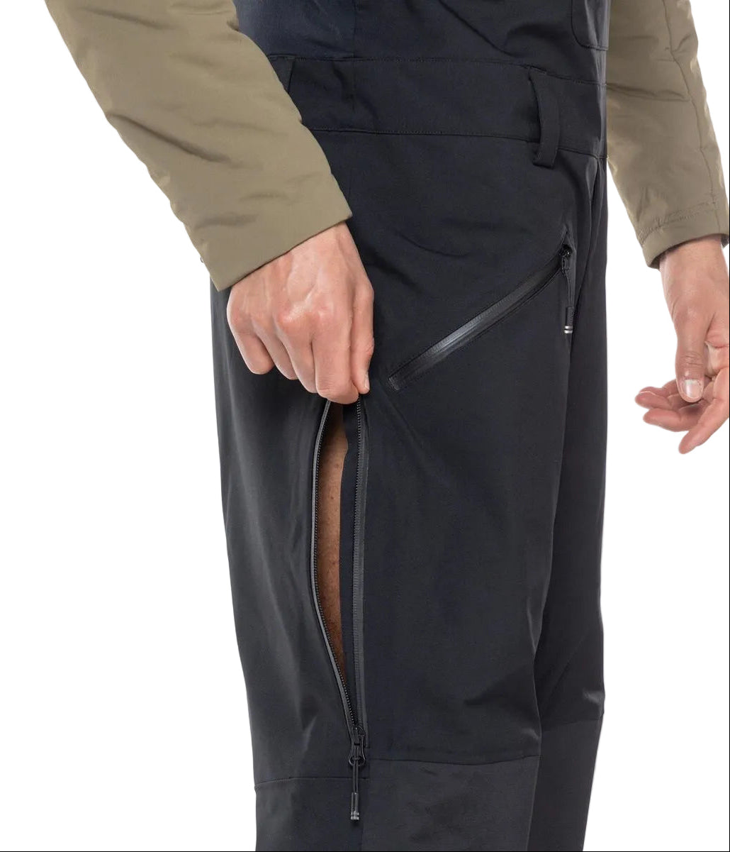 A close-up of a man wearing a pair of black Rossignol Men's SKPR 3L AYR Bib Pants that are waterproof, breathable, stretchable, warm, and include vents.