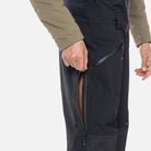 A close-up of a man wearing a pair of black Rossignol Men's SKPR 3L AYR Bib Pants that are waterproof, breathable, stretchable, warm, and include vents.