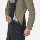 A close-up of a man wearing a pair of black Rossignol Men's SKPR 3L AYR Bib Pants that are waterproof, breathable, stretchable, warm, and include vents.