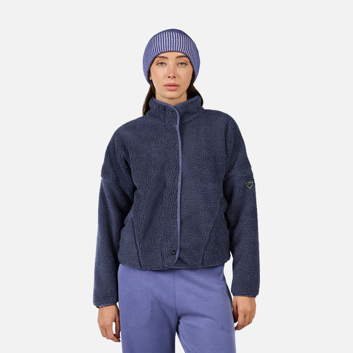 A woman wearing a purple fleece Rossignol Women's All Track Snap Sherpa Jacket that is moisture-wicking, breathable, and warm.