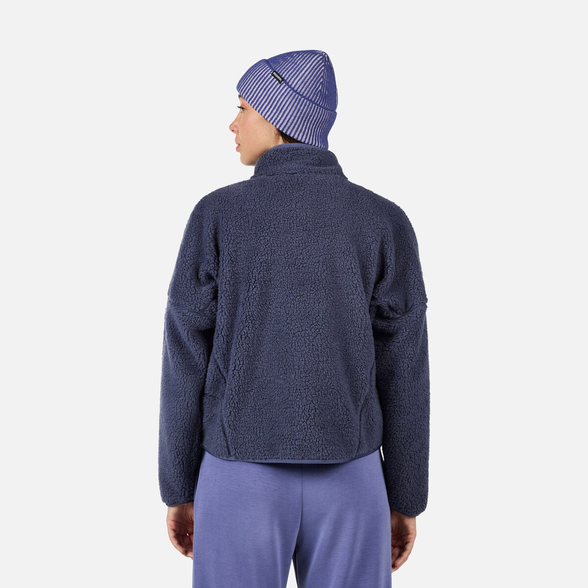 A woman wearing a purple fleece Rossignol Women's All Track Snap Sherpa Jacket that is moisture-wicking, breathable, and warm.