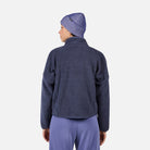 A woman wearing a purple fleece Rossignol Women's All Track Snap Sherpa Jacket that is moisture-wicking, breathable, and warm.