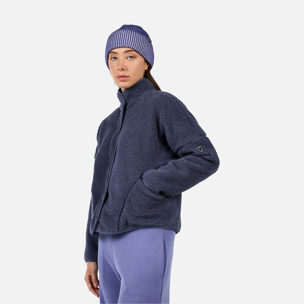 A woman wearing a purple fleece Rossignol Women's All Track Snap Sherpa Jacket that is moisture-wicking, breathable, and warm.