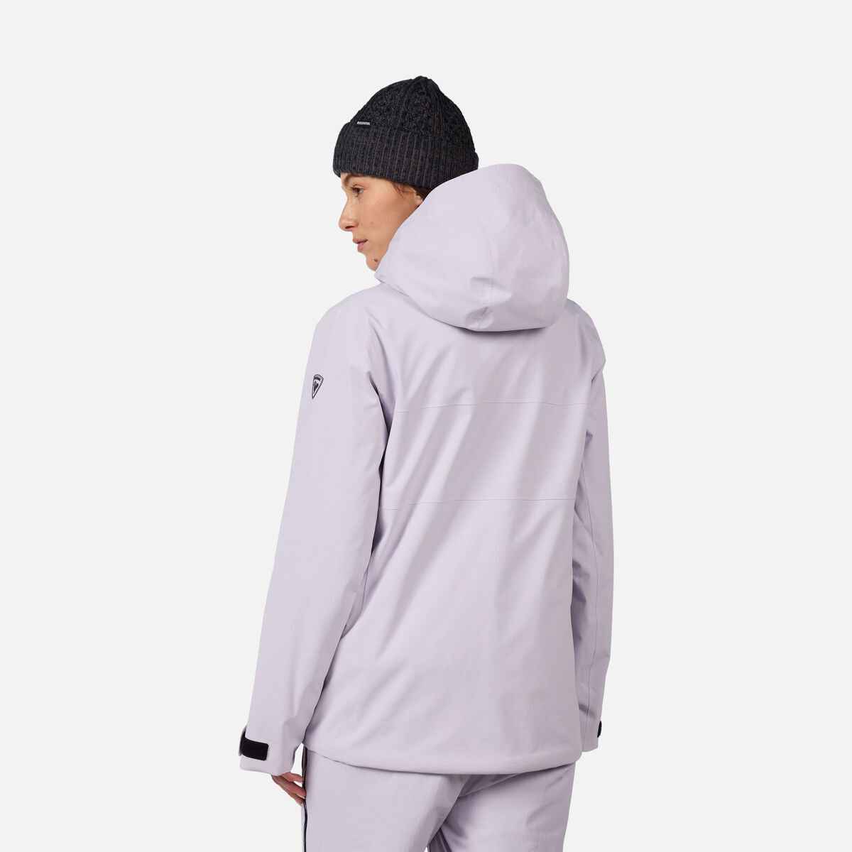 A woman wearing a light purple Rossignol Women's Desafio 2L Shell Ski Jacket that is lightweight, waterproof, breathable, and stretchable.