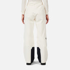 A woman wearing a pair of white Rossignol Women's Insulated Ski Pants that are waterproof, breathable, stretchable, and warm.
