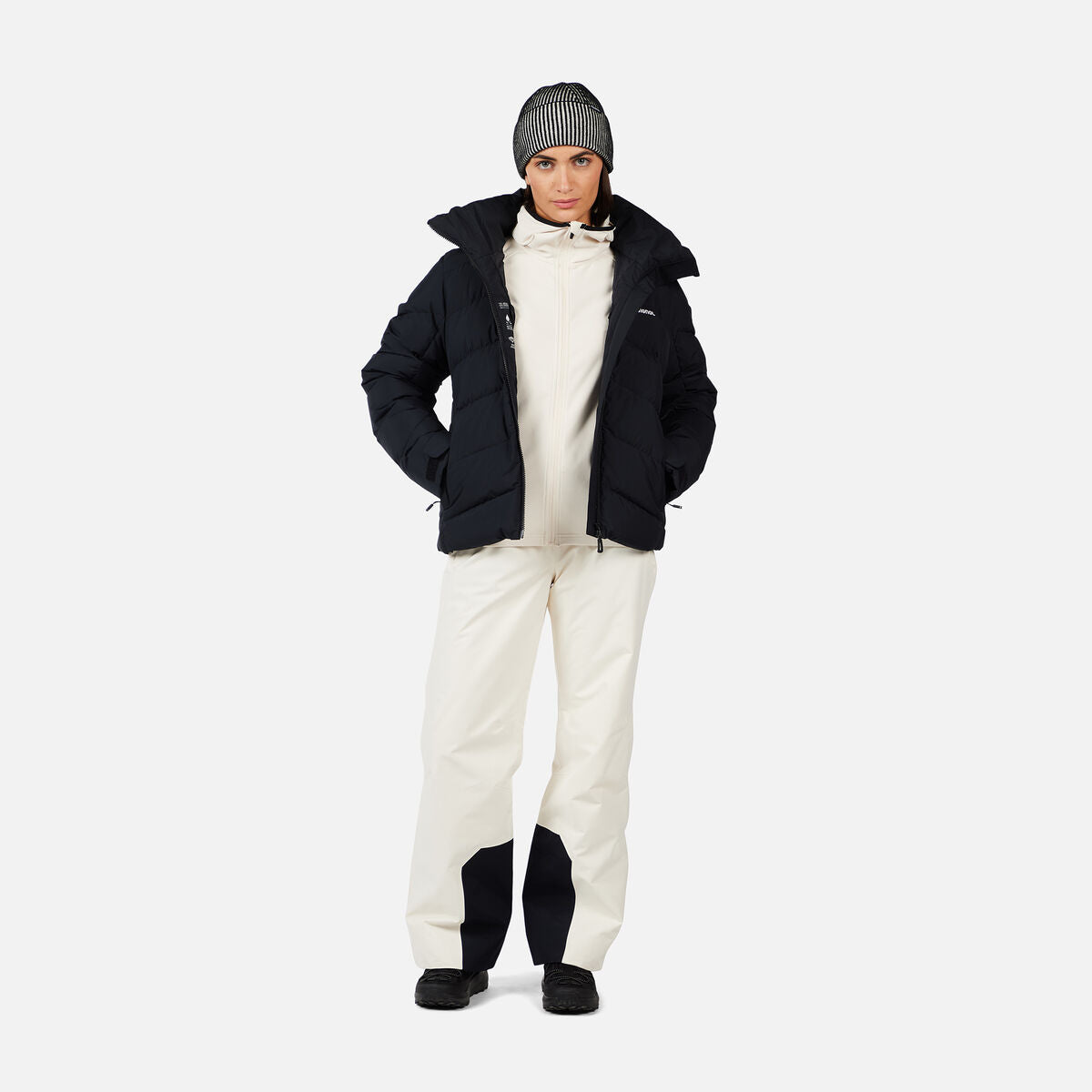 A woman wearing a pair of white Rossignol Women's Insulated Ski Pants that are waterproof, breathable, stretchable, and warm.