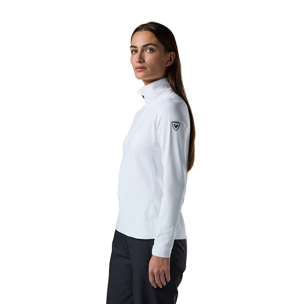 Side view of a white Rossignol Women’s Midlayer Stretch 1/2 Zip Sweater featuring multi-directional stretch knit, thermal fleece interior, deep half-zip front zipper, and an ergonomic stand-up collar.