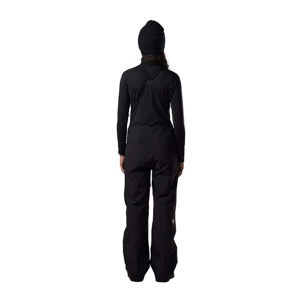 Rear view of black Rossignol Women’s Outerlimits Insulated Bib Pants featuring high-chest bib construction, waterproof membrane fabric, adjustable suspenders, zippered inner thigh vents, integrated boot gaiters, and reinforced hem scuff guards.