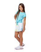 A girl wearing a white Sofibella Girls Spectrum UV Skort with a multicolour design on a white background.