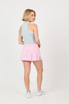 Woman wearing a grey top and pink Sofibella UV Staples 14" Panel Skort on a white background