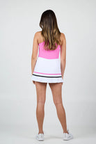 Woman wearing a pink tank top and white Sofibella Women's Style Icon 14" Skort with black and pink stripes on a white background